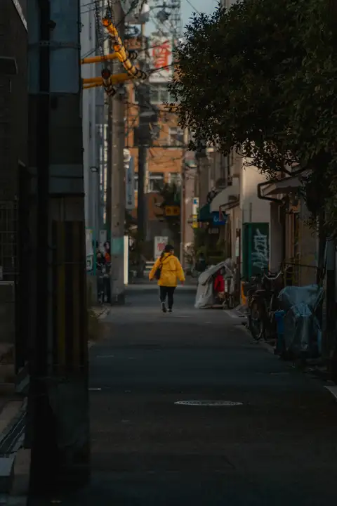 A solitary pedestrian walking through a narrow shadowed city street