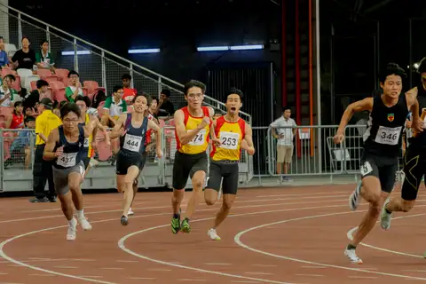 Student sprinters racing around the bend inside the National Stadium