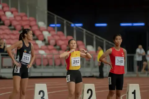 Three student athletes waiting beside their lane markers before a race