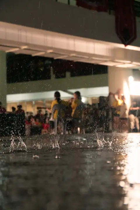 Water splashing across a lit courtyard with students gathered behind