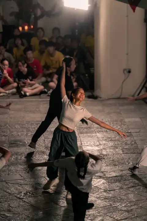 Sheryl smiling with both arms extended during a courtyard dance performance