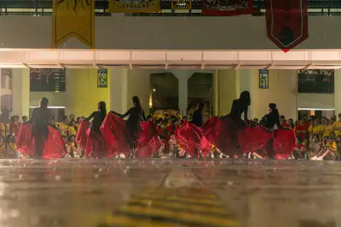 A line of student dancers holding wide red skirts before their peers